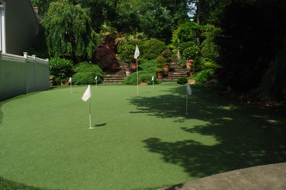 Naperville Synthetic grass golf green with flags in a landscaped backyard