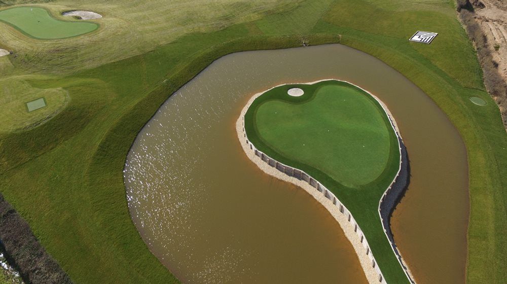 Naperville Aerial view of a vibrant green synthetic grass island in a natural pond on a golf course